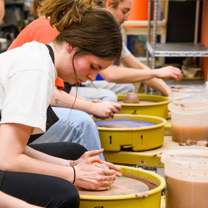 students working with clay at pottery wheels