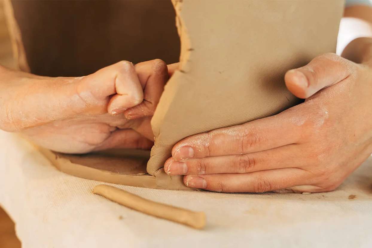 hands assembling body of a clay teapot
